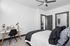 Modern bedroom with sleek decor featuring a cozy bed, stylish desk area, and ceiling fan, creating a tranquil and inviting space.