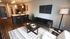 Modern open-concept living space with sleek kitchen, stylish decor, and cozy seating area, featuring dark wood accents and contemporary lighting.
