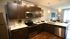 Modern kitchen with sleek dark wood cabinets, stainless steel appliances, and a cozy breakfast bar opening to a bright, inviting living area.
