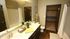 Elegant bathroom with double vanity, gleaming surfaces, chic decor, and access to a spacious walk-in closet.