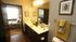 Chic apartment bathroom with a dual-sink vanity, elegant decor, and a glimpse of a cozy bedroom.