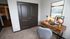 Cozy home office corner featuring a rustic wooden desk, plush grey chair, and vibrant artwork, perfect for focused work sessions.
