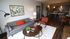 Contemporary apartment living room with stylish gray sofa, vibrant artwork, and open-concept kitchen.