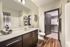 Modern bathroom with sleek fixtures, elegant mirror, and inviting walk-in closet, highlighted by warm wood floors and stylish decor.