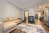 Modern apartment living room with cozy beige sectional, elegant rug, and sleek open kitchen, offering a warm and inviting atmosphere.