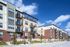 Modern apartment complex showcasing contemporary design with spacious balconies, surrounded by lush greenery and clear blue skies.