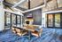 Modern conference room with stylish decor, featuring a sleek wooden table, leather chairs on wheels, and natural light from floor-to-ceiling windows.