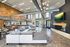 Luxury open-concept living area with modern industrial design, featuring high ceilings, large windows, and stylish furnishings in a spacious apartment.