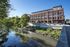 Charming riverside brick building featuring Northern Indiana Supply Company, surrounded by lush greenery and reflecting on calm waters.
