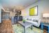 Elegant open-concept apartment featuring a modern kitchen, cozy living area with stylish decor, and warm wooden flooring.