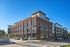 Charming brick apartment complex with modern balconies and lush landscaping under a clear blue sky.