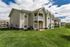 Charming apartment complex featuring beautiful balconies, lush green lawns, and spacious outdoor areas under a clear blue sky.