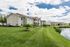 Charming apartment complex with beautifully manicured lawns and serene lakeside views under a bright blue sky.