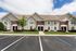 Charming townhouse complex with classic brick and siding facade, surrounded by lush greenery and ample parking spaces.