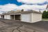 Charming row of garages with well-maintained beige siding, neatly arranged along a pristine driveway under a bright blue sky.