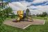Inviting playground with a vibrant yellow spiral slide and swings set against a lush green park, perfect for family fun and relaxation.