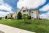 Charming suburban apartment complex with elegant architecture, manicured lawns, and bright blue skies, offering a peaceful neighborhood vibe.