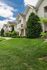 Charming suburban townhouses featuring well-manicured lawns, elegant balconies, and beautiful siding under a bright blue sky.