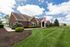 Charming brick residential building with manicured lawn and colorful flags, perfect for a cozy home.