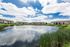Serene apartment community by a picturesque pond with lush greenery, perfect for tranquil living with stunning views.