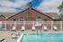 Inviting outdoor pool area with comfortable lounge chairs, set against a charming brick clubhouse and bright blue sky.