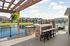 Charming outdoor patio with a lakeside view, featuring a stylish pergola and modern grill station next to a refreshing pool area.