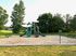 Charming playground view with vibrant slides and swings, surrounded by lush greenery and spacious benches.
