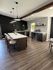 Modern kitchen showcasing elegant dark cabinetry, a sleek island with bar stools, and ambient pendant lighting, perfect for entertaining.