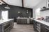 Modern kitchen with sleek dark cabinets, stainless steel appliances, and open shelving against a stylish black accent wall, offering a chic and contemporary vibe.
