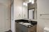 Modern bathroom with sleek black countertop, elegant mirror, and stylish lighting fixtures providing a sophisticated ambiance.