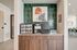 Chic coffee station with modern artwork and sleek cabinetry in a stylish apartment lounge.