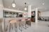 Modern open-concept kitchen with elegant tiled backsplash, stylish pendant lighting, and chic bar seating in a sophisticated apartment setting.