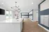 Modern apartment lobby with sleek white countertop, stylish chandelier, and organized mailboxes. Bright and welcoming space with wood flooring.