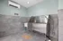 Modern pet washing station with a stainless-steel tub and sleek gray tile walls, featuring a decorative bone-shaped mat.