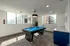 Bright game room with modern blue pool table, elegant lighting, and large windows offering a pleasant view.