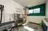 Modern utility room featuring a stainless steel pet wash station, vibrant green accent wall, and large window for natural light.