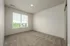 Bright bedroom with plush carpeting and large window offering serene views, perfect for relaxation.