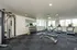 Modern fitness center featuring state-of-the-art gym equipment, including treadmills, weight racks, and a multi-functional machine, with ample natural light from large windows.
