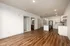 Modern open-plan apartment with elegant hardwood floors, bright kitchen area featuring sleek cabinetry, and inviting pendant lighting. Spacious design perfect for contemporary living.