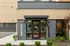 Modern leasing office entrance with sleek glass door, stylish lighting, and inviting greenery.