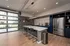Modern communal kitchen with sleek gray countertops, stylish pendant lighting, and stainless steel appliances in an open-concept space.