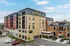 Modern urban apartment building with sleek design and vibrant exterior, set against a clear blue sky, enhancing the appeal of city living.