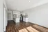 Bright open-concept living space with modern kitchen, featuring sleek cabinets, stainless steel appliances, and stylish wood flooring.