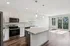 Elegant open-concept kitchen with modern appliances and a spacious island adjacent to a bright living area with large windows and a scenic view.