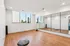 Chic and modern fitness room with mirrored wall, large windows offering a city view, and sleek wood flooring.