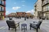 Spacious outdoor lounge area with stylish seating, perfect for relaxation, surrounded by modern apartments under a clear blue sky.
