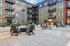 Elegant apartment complex courtyard with modern patio furniture, vibrant green spaces, and charming balconies.