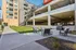 Modern apartment exterior with inviting outdoor seating area, lush green lawn, and convenient access to parking and stairs.