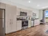 Modern kitchen with sleek wooden cabinetry, stainless steel appliances, and a sunny office nook with expansive city views.