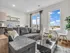 Bright, modern living room with a plush gray sectional, sleek black coffee table, and dining nook offering stunning city views.